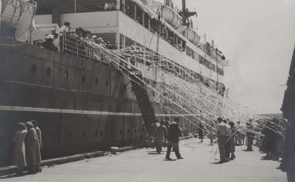 Crowd on Station Pier, Port Melbourne, holding streamers as a ship departs in 1952